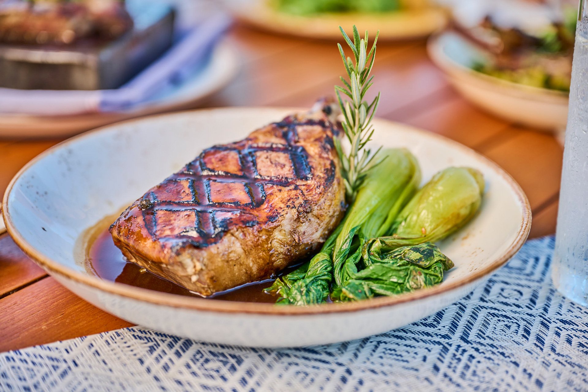 A perfectly seared steak with roasted vegetables and rosemary sprig on a plate