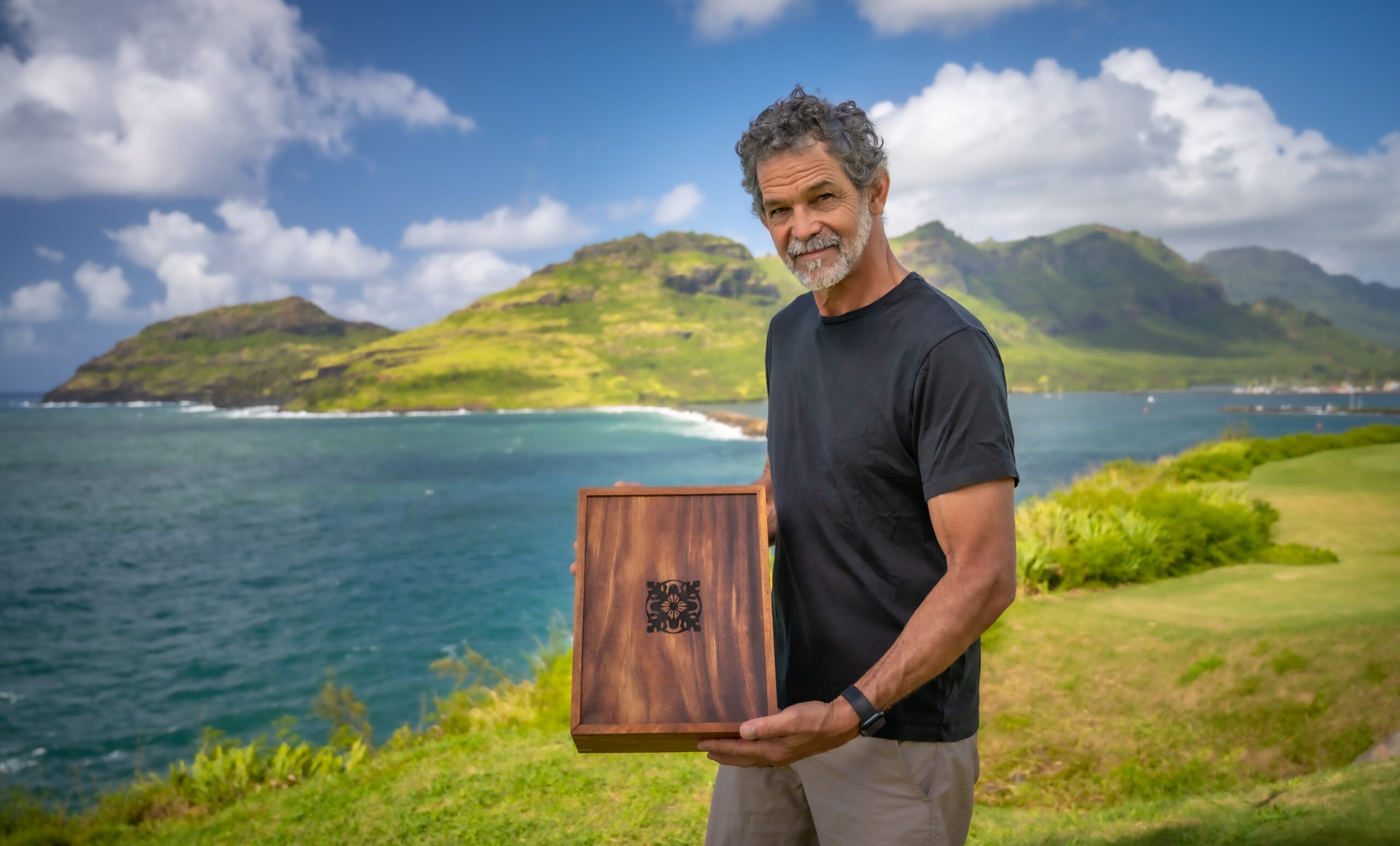 Leleo Kinimaka shows a piece of wordwork in front of blue water